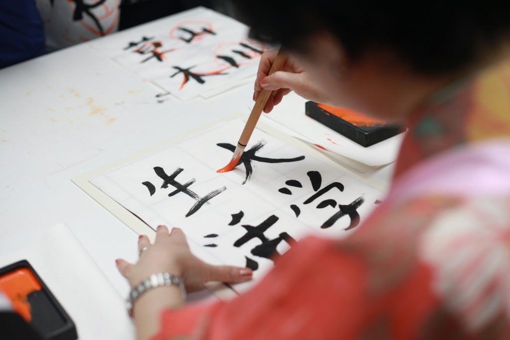 pexels-photo-1498273-1498273 Close-up of a person practicing traditional Japanese calligraphy with a brush on paper.