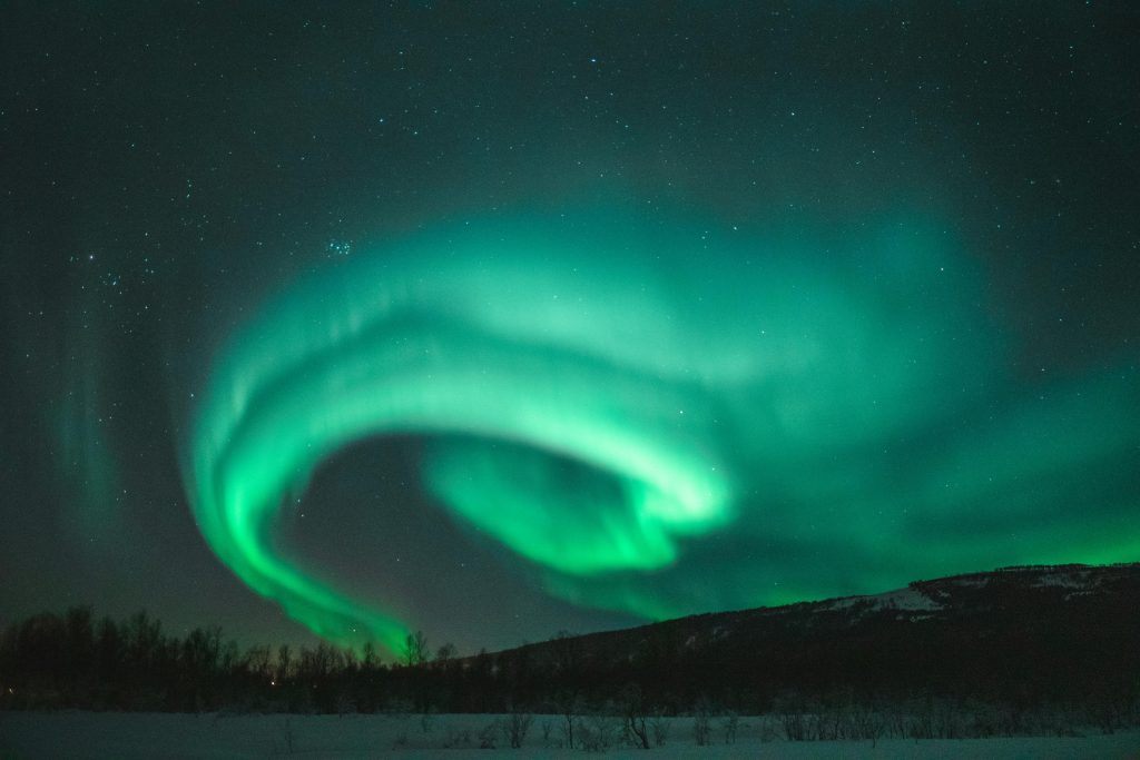 pexels-photo-1938348-1938348 Captivating view of the Northern Lights dancing above a snowy landscape under a starry night sky.